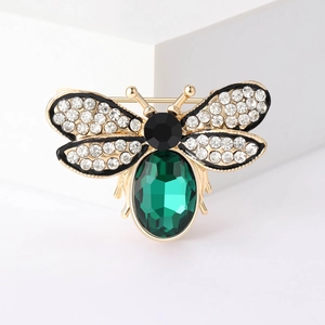 Exquisite gold bee brooch with emerald green gem and sparkling rhinestone wings on white