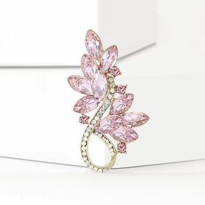 Elegant gold-tone leaf brooch with pink marquise crystals on a white stone base