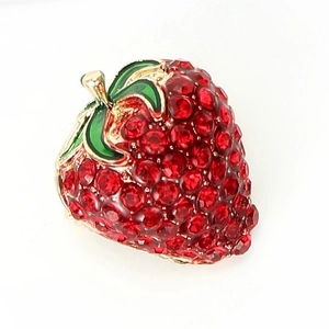 Vue détaillée de la broche fraise avec strass rouges et feuille émaillée verte