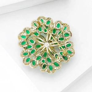Goldene Blumenbrosche mit smaragdgrünen Zirkonia zeigt Rückseite der feinen Brosche