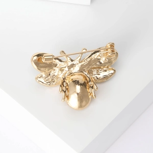 Cute gold bee brooch showing the high-quality metal back texture and safety pin clasp