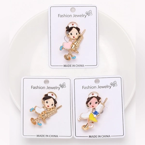 Detailed macro view of three cute cartoon nurse enamel brooches on white cardstock