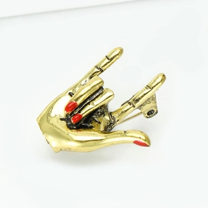 Creative gold five-finger gesture brooch with red enamel nails on white background