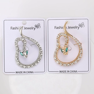 Detailed macro view of snake brooches with silver and gold finishes and green gem eyes