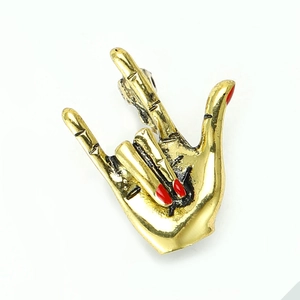 Detailed macro of golden hand gesture brooch with vibrant red enamel nails and retro finish