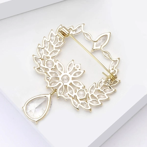 Close-up of golden olive branch wreath brooch with pear-shaped zircon drop and stones