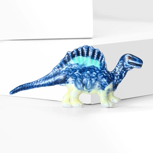 Detail view of a blue rhinestone dinosaur brooch with glossy finish on a white background