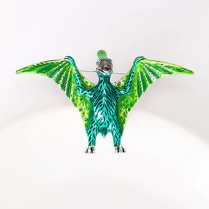 Detail view of a green enamel pterosaur brooch with intricate wings and metal pin back