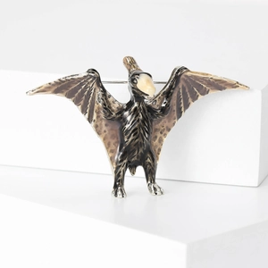 Macro detail of vintage pterosaur brooch with spotted wings and metal pin clasp