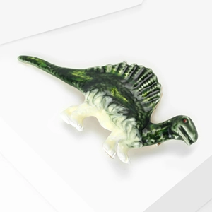 Detail view of Spinosaurus brooch with green enamel coating and rhinestone accents
