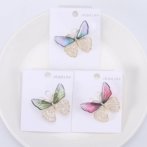 Close-up of butterfly brooches with colorful gradient wings and intricate hollow patterns