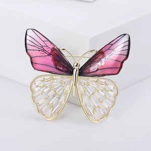 Macro detail of a crystal butterfly brooch with purple resin wings and gold plating