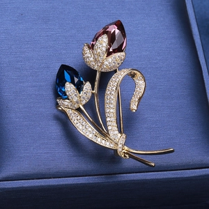 Broche tulpe dorée exquise avec cristaux rouges et bleus sur une boîte à bijoux