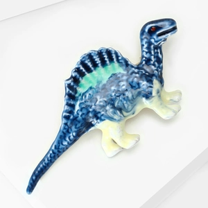 Macro detail of dinosaur brooch with blue and white enamel gradient and green accents