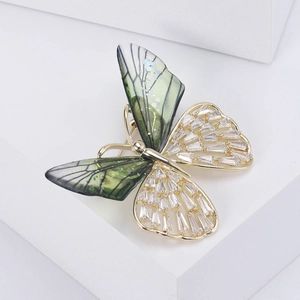 Macro shot of butterfly brooch with green wings and rectangle cubic zirconia stones