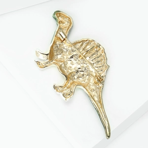 Detailed back view of golden dinosaur brooch showing textured metal and safety pin closure