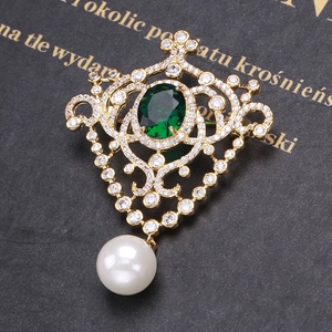 Macro detail of vintage medal brooch with emerald zircon and hanging pearl detail