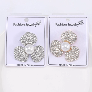 Détail macro de broches en forme de fleurs avec strass et perles sur cartes de bijoux