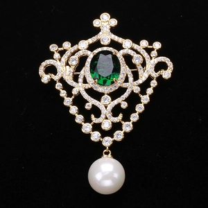 Detailed macro view of vintage baroque brooch with emerald gem, zircon and pearl drop