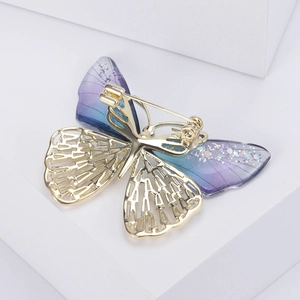 Detailed back view of a butterfly brooch showing the metal pin and golden mesh wings