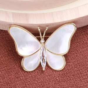 Close-up of golden butterfly brooch featuring white mother of pearl and marquise zircon