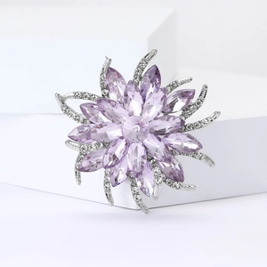 Détail d'une broche fleur en cristal violet avec feuilles argentées et pavage de diamants