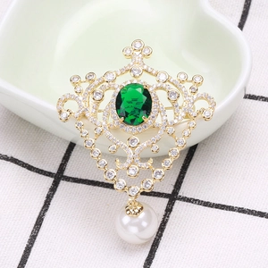 Detailed close-up of a vintage court-style brooch with emerald gemstone and pearl drop