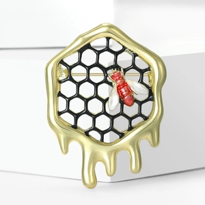 Détail de la broche alvéole dorée avec petite abeille rouge et émail goutte de miel