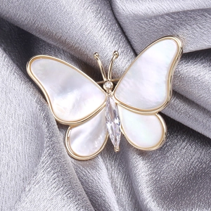 Macro shot of butterfly brooch with shell inlay and cubic zirconia on silk cloth