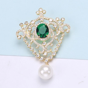 Close-up of vintage medal brooch with emerald stone, small diamonds and pearl pendant
