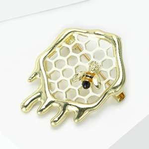 Détail de la broche avec cadre doré fondant, grille en nid d'abeille et petite abeille