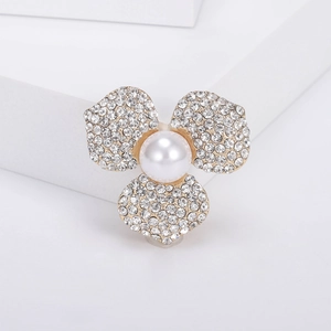 Détail d'une broche fleur à trois pétales ornée de strass et d'une perle centrale