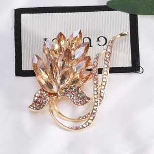 Macro shot of flower brooch with amber crystals and rainbow rhinestones on white silk