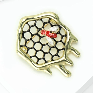 Vue détaillée de la broche abeille dorée avec maille nid d'abeille noire et émail poli