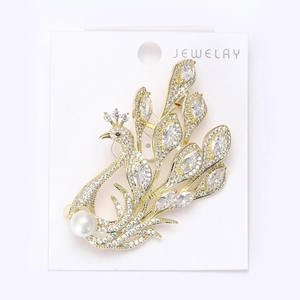 Close-up of golden peacock brooch with sparkling white rhinestones and a pearl accent