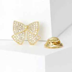Elegant gold bow brooch with sparkling cubic zirconia on a minimalist geometric display