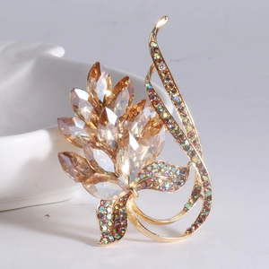 Macro shot of leaf-shaped brooch with champagne crystals and colorful rhinestones