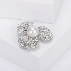Détail d'une élégante broche fleur argentée avec perle blanche et strass étincelants