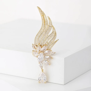 Close-up of golden angel wing brooch with marquise stones and teardrop zircon drop