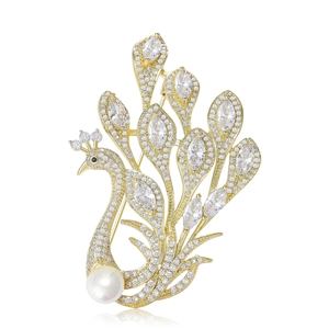 Golden peacock brooch with sparkling crystals and pearl on a white background