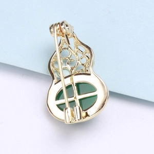 Detail view of the golden metal hollow gourd brooch back with a green jade stone inlay