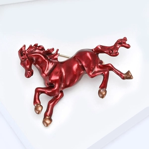 Macro detail of the deep red enamel running horse brooch with golden alloy accents