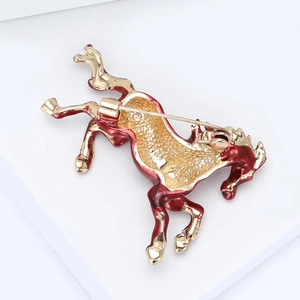 Detail view of the back of a gold horse brooch with red enamel and safety pin clasp