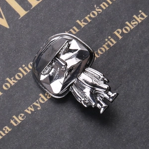 Detailed macro view of silver metallic alloy mask brooch with reflective finish and details