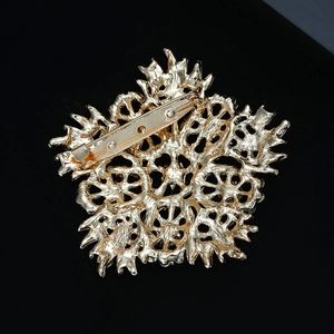 Detailed back view of golden flower brooch featuring hollowed pattern and pin clasp