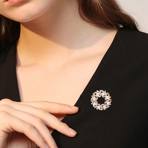 Elegante broche de corona de perlas doradas con motivos florales en una prenda negra