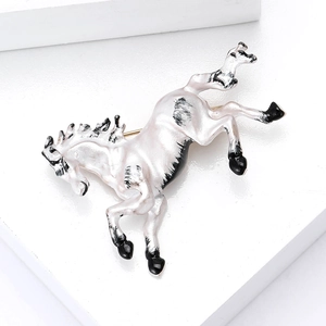 Detail of white enamel horse brooch with black accents on minimalist white display base
