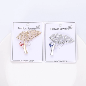Vue détaillée de broches en forme d'arbre en or et argent avec oiseaux émaillés