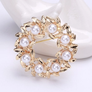 Detalle del elegante broche de corona dorada con perlas blancas en soporte de mano