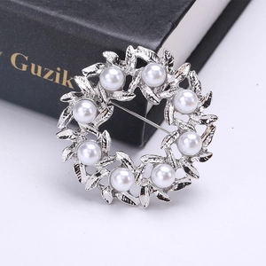 Detalle del broche de corona de perlas plateadas con hojas elegantes y perlas blancas